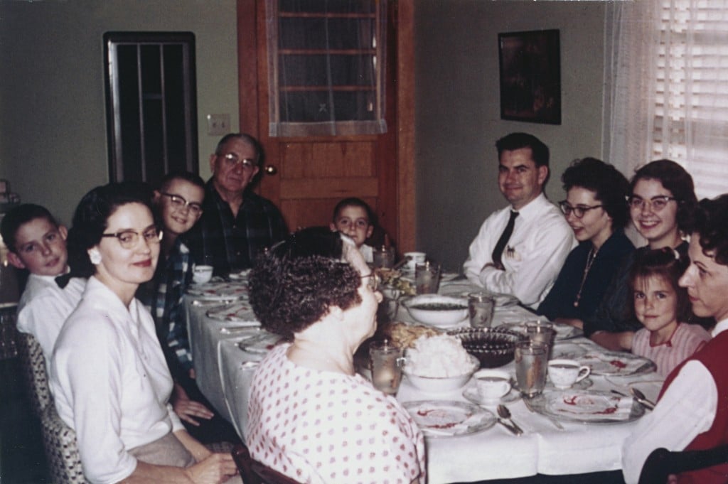 Family sitting down for meal together around dinner table