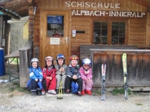 5 children sitting outside ski cabin
